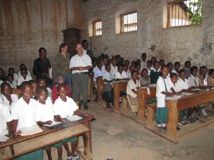 1 22 er zitten best veel kindjes op een rijtje in een bankje in het klaslokaal van de primary school, en dat terwijl het regende